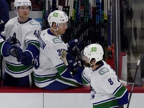 Winger Conor Garland skates by the Canucks bench, getting congratulated by teammates including Elias Pettersson (left) with whom he has found some on-ice chemistry of late — albeit in a brief sample size.