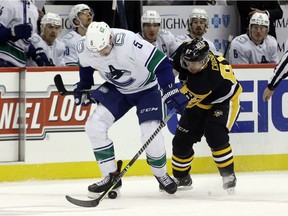 Vancouver Canucks defenceman Tucker Poolman and Pittsburgh Penguins captain Sidney Crosby fight to control the puck on Nov. 24, 2021.