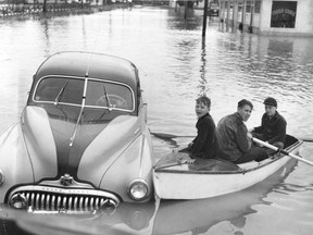 Three boys in a rowboat and a partially submerged Buick in the Fraser Valley flood 1948. There was no location given with this photo, but it might be Rosedale. John McGinnis/ Province