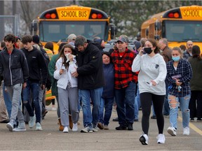 Parents walk away with their kids from the Meijer's parking lot where many students gathered following an active shooter situation at Oxford High School in Oxford, Michigan, U.S. November 30, 2021.
