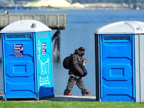 A man walks past portable toilets in Crab Park in Vancouver.