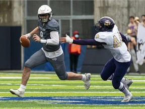 Notre Dame Jugglers quarterback Aiden Domino tries to escape the pressure of Vancouver College Fighting Irish Alex Kahwaji during high school football action at Notre Dame in Vancouver Nov., 6, 2021.