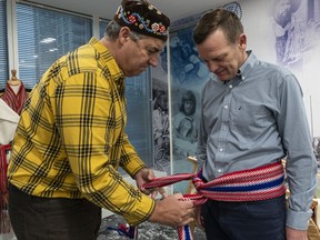 Métis Nation director Louis De Jaeger, left, presents Darrell Fox, brother of Terry Fox, is a traditional Métis sash.