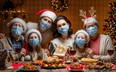 Merry Christmas! Happy family are having dinner at home. Celebration holiday and togetherness near tree. People are wearing facemasks.