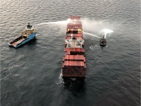 Tugboats pour water on the container ship Zim Kingston after it caught fire the day before off the coast of Victoria, British Columbia, Canada October 24, 2021. Canadian Coast Guard/Handout via REUTERS. THIS IMAGE HAS BEEN SUPPLIED BY A THIRD PARTY.