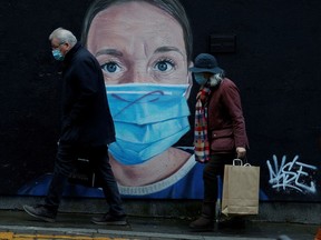 FILE PHOTO: People wearing face masks walk past a mural of a nurse in the centre of Manchester, Britain, November 29, 2021. REUTERS/Phil Noble/File Photo