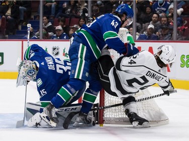Vancouver Canucks goalie Thatcher Demko (35) covers up the puck as Quinn Hughes (43) checks Los Angeles Kings' Phillip Danault (24) during first period NHL hockey action in Vancouver, B.C., Monday, Dec. 6, 2021.