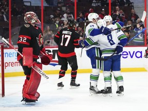 Ottawa Senators goaltender Filip Gustavsson looks up as Vancouver Canucks' Bo Horvat, left to right, Conor Garland and Tanner Pearson celebrate a goal during first period NHL action in Ottawa on Wednesday, Dec. 1, 2021.