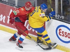 Sweden's Oskar Magnusson fights for control of the puck with Russia's Dmitri Zlodeyev during first period during IIHF World Junior Hockey Championship action in Red Deer, Alberta on Sunday, December 26, 2021.