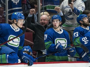 Head coach Bruce Boudreau, arms raised in celebration behind the Canucks bench after a Rogers Arena win earlier this season, ‘makes the team feel good’ with his positive energy.