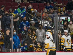 Pittsburgh Penguins defenceman Brian Dumoulin (8) picks up a Vancouver Canucks forward Bo Horvat (53) jersey that a Vancouver fan threw on the ice near the end of regulation time in the third period at Rogers Arena.