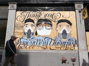 A man walks past a murals painted on the side of a building in Gastown that honours respiratory therapists during the battle against the spread of the COVID-19 virus.