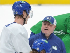 Canucks head coach Bruce Boudreau talks with Tyler Myers during practice at Rogers Arena in Vancouver on Dec. 7.