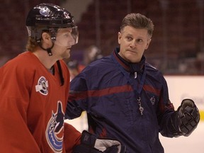 Vancouver Canucks coach Marc Crawford, who replaced Mike Keenan in March 1999, talks to captain Markus Naslund during a 2004 practice.