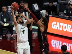 Fardaws Aimaq of the Utah Valley Wolverines takes a shot over defender Evan Gilyard II of the New Mexico State Aggies during a semifinal game of the Western Athletic Conference basketball tournament in Las Vegas, Nev., on March 12, 2021.