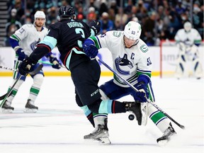 SEATTLE, WASHINGTON - JANUARY 01: Will Borgen #3 of the Seattle Kraken and Bo Horvat #53 of the Vancouver Canucks battle for a loose puck during the first period at Climate Pledge Arena on January 01, 2022 in Seattle, Washington.