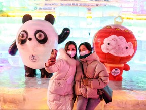 This photo taken on Jan. 15, 2022 shows visitors posing for selfies with ice sculptures of Bing Dwen Dwen, left, and Shuey Rhon Rhon, respective mascots of the 2022 Beijing Winter Olympic and Paralympic Games, in Beijing.