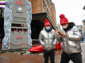 Two men walk past a countdown installation for the Beijing 2022 Winter Olympic Games which begin in two weeks time, in Beijing on January 20, 2022.