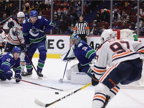 Vancouver Canucks' Quinn Hughes (43) dives to reach the puck against Edmonton Oilers' Connor McDavid (97) in front of Vancouver goalie Spencer Martin (30) during the first period of an NHL hockey game in Vancouver, on Tuesday, January 25, 2022.