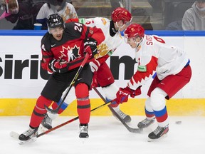 Canada's Justin Sourdif (24), battles for the puck with Russia's Kirill Steklov (6) and Fedor Svechkov (9) during second period IIHF World Junior Hockey Championship exhibition action in Edmonton, Thursday, Dec. 23, 2021.