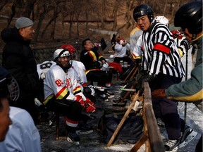 Ice hockey players take a break at a makeshift ice rink on a frozen lake, in Anshan, Liaoning province, China, January 1, 2022.