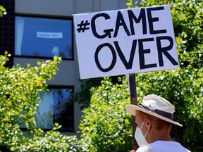 A pro-refugee protester holds a 'game over' sign outside the Park Hotel, where Serbian tennis player Novak Djokovic is believed to be held while he stays in Melbourne, Australia, on Jan. 9, 2022.