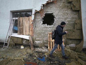 A local resident of the Ukrainian-controlled village of Stanytsia Luhanska walks among debris after the shelling by Russia-backed separatists on February 18, 2022.