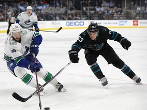 Vancouver Canucks defenseman Kyle Burroughs skates for the puck as San Jose Sharks left winger Matt Nieto defends during the first period of an NHL hockey game in San Jose, Calif., on Thursday, February 17 2022.