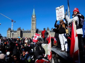 Protestors stand in front of the Parliament building in Ottawa as truckers take part in a convoy to protest mandates for cross-border truck drivers.