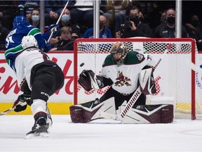 Vancouver Canucks' Elias Pettersson, back left, scores against Arizona Coyotes goalie Karel Vejmelka during the second period of an NHL hockey game in Vancouver, on Tuesday, February 8, 2022.