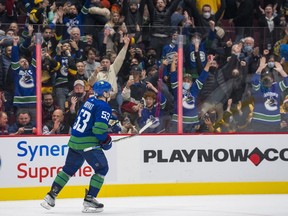 Canucks fans, both masked and unmasked, celebrate a Rogers Arena goal by captain Bo Horvat earlier this NHL season.
