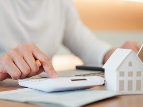 close up young man hand press on calculator to check and summary expense of home loan mortgage for refinance plan , people lifestyle concept