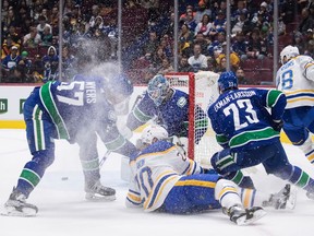 Vancouver Canucks goalie Thatcher Demko, back centre, makes the save as Buffalo Sabres' Cody Eakin (20) falls in front of Vancouver's Tyler Myers (57) and Oliver Ekman-Larsson (23) during the first period of an NHL hockey game in Vancouver, B.C., Sunday, March 20, 2022. ORG XMIT: VCRD210_2022032102