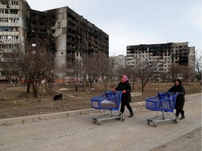 People push carts near blocks of flats, which were damaged during Ukraine-Russia conflict in the besieged southern port city of Mariupol, Ukraine March 17, 2022.