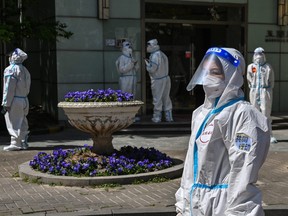 Workers and volunteers look on in a compound where residents are tested for COVID-19 during the second stage of a pandemic lockdown in Jing' an district in Shanghai on April 4, 2022.