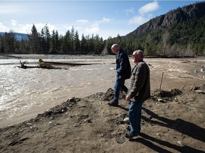 Paulus Velt, front right, whose home was washed away and farm destroyed during the November floods, shows B.C. Minister of Public Safety and Solicitor General Mike Farnworth where his farm was on the Nicola River, west of Merritt, B.C., on Thursday, March 24, 2022.