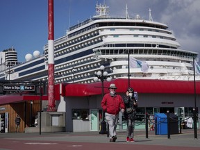 Passengers walk to a tour bus after disembarking from the Holland America Koningsdam cruise ship, in Victoria, Saturday, April 9, 2022. The cruise ship is the first to call to a Canadian port since prior to the start of the COVID-19 pandemic. According to the Greater Victoria Harbour Authority, 358 ship visits carrying an estimated 780,000 passengers are expected in the city this year.