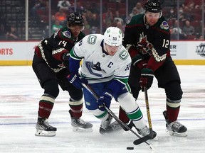 Vancouver Canucks center Bo Horvat (53) moves the puck against Arizona Coyotes defenseman Shayne Gostisbehere (14) and left wing Nick Ritchie (12) during the first period at Gila River Arena.