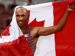 Damian Warner of Canada celebrates with his national flag after winning gold at the 2020 Tokyo Olympics.