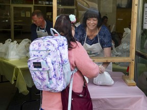 Former addict Laura Harvey hands-out meals as people lined-up around the block to receive an Easter meal at the Union Gospel Mission in Vancouver on Saturday, April 16, 2022.