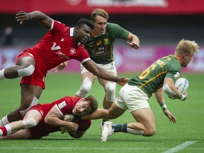 Canada's Matt Oworu and Phil Berna tackle South Africa's JC Pretorius in the HSBC World rugby Sevens Series at BC Place Stadium in Vancouver, BC Saturday, April 16, 2022.