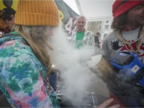 A person inhales smoke from the back of a leaf blower a vendor was using to send marijuana smoke out over the crowd during the 4-20 marijuana celebration, in Vancouver, on Wednesday, April 20, 2022.