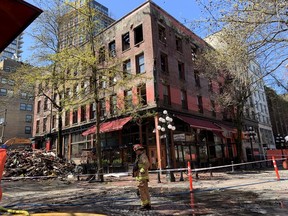 A firefighter walks in front of the Winters Hotel at 203 Abbott and Water Streets Friday. The 1907 hotel had a devastating fire April 11, and is being demolished. But a body has been found in the ruins and demolition was temporarily halted Friday. John Mackie/PNG April 22, 2022