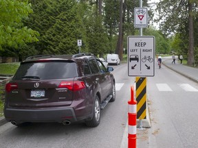 Cars and a cyclist in their respective lanes in Stanley Park.