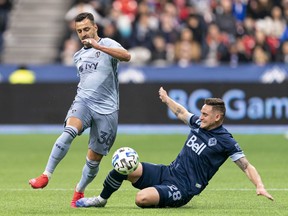 Luis Martins of Sporting Kansas City tries to break away from a slide tackle of Jake Nerwinski of the Vancouver Whitecaps during a 2020 MLS game at BC Place. Martins joined the team as a free agent on Wednesday.
