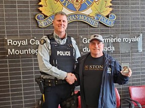 Kelowna RCMP Const. Mike Della-Paolera returns the 1979 Wayne Gretzky rookie hockey card to Ian Moore. It was stolen in 2015 and finally returned to its owner last week.