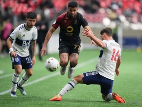 Valour FC's Federico Pena (77) jumps to avoid the tackle by Vancouver Whitecaps' Sebastian Berhalter (16) as Ryan Raposo (27) watches during the first half of a preliminary round Canadian Championship soccer match, in Vancouver, on Wednesday, May 11, 2022.