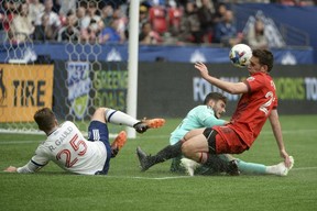 Toronto FC goaltender Alex Bono (25) and defender Shane O'Neill (27) defend against Vancouver Whitecaps midfielder Ryan Gauld (25) in the first half at BC Place.
