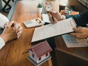 Agents are using pens pointing to contracts and are being explained to customers at the office.