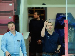 Vancouver Canucks president & general manager Mike Gillis (left) watches director of hockey administration Jonathan Wall (right) toss a puck onto the ice prior to the team’s practice at Boston University’s Walter Brown Arena JUNE 7, 2011.